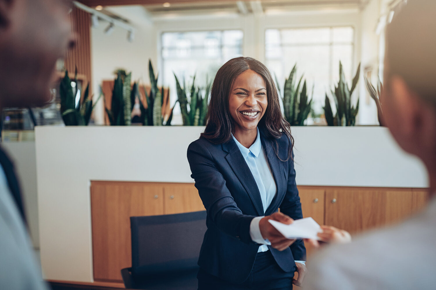 Smiling African American concierge working behind a hotel counter giving two guests their hotel information during check in